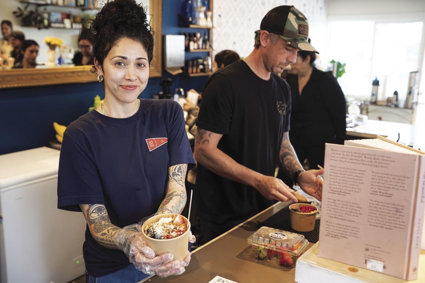 A Golden Sol team member holding a fresh açaí bowl behind the counter