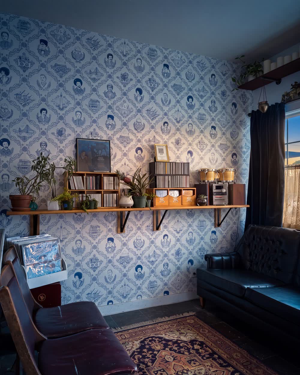 The seating corner at Golden Sol — patterned wallpaper, a record shelf, plants and a leather chair